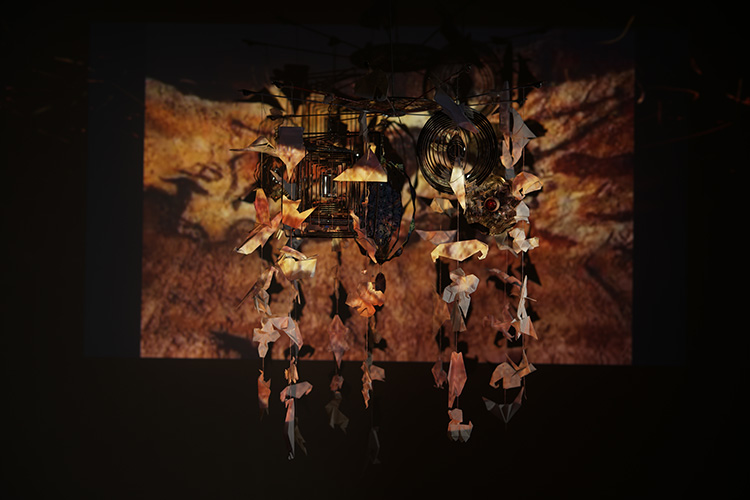 鉄と和紙で作られた動物のモビール作品、背景に洞窟壁画の映像が投影されたインスタレーション