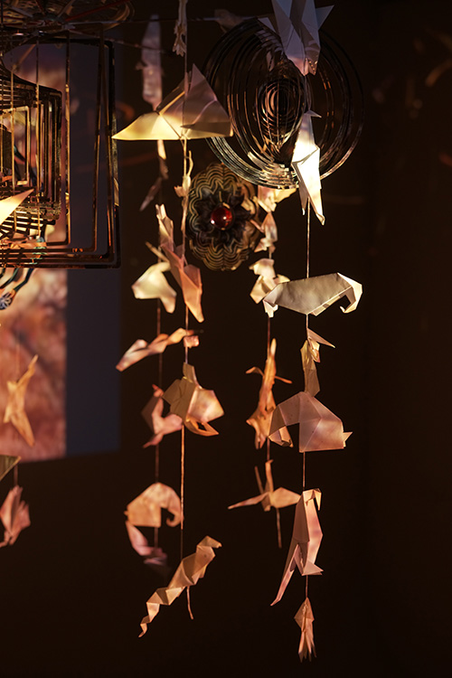 鉄と和紙で作られた動物のモビール作品、背景に洞窟壁画の映像が投影されたインスタレーション